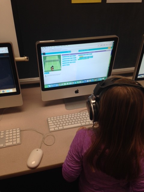 A student at a computer with headphones on