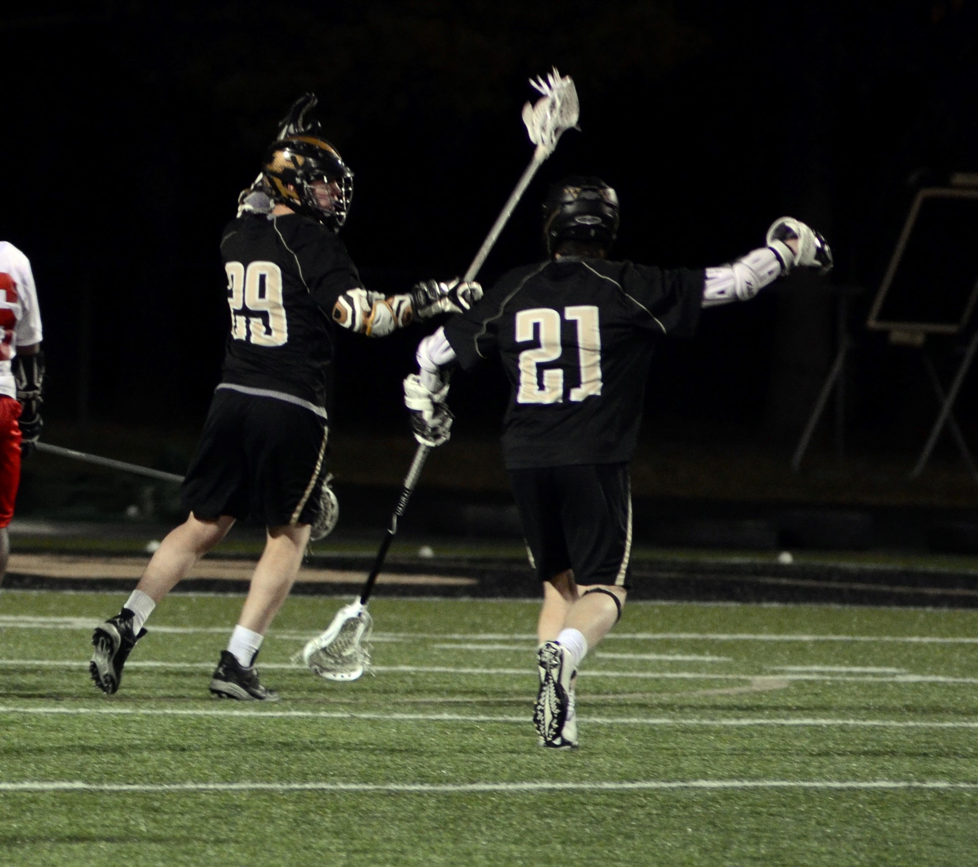 two lacrosse players on the field.