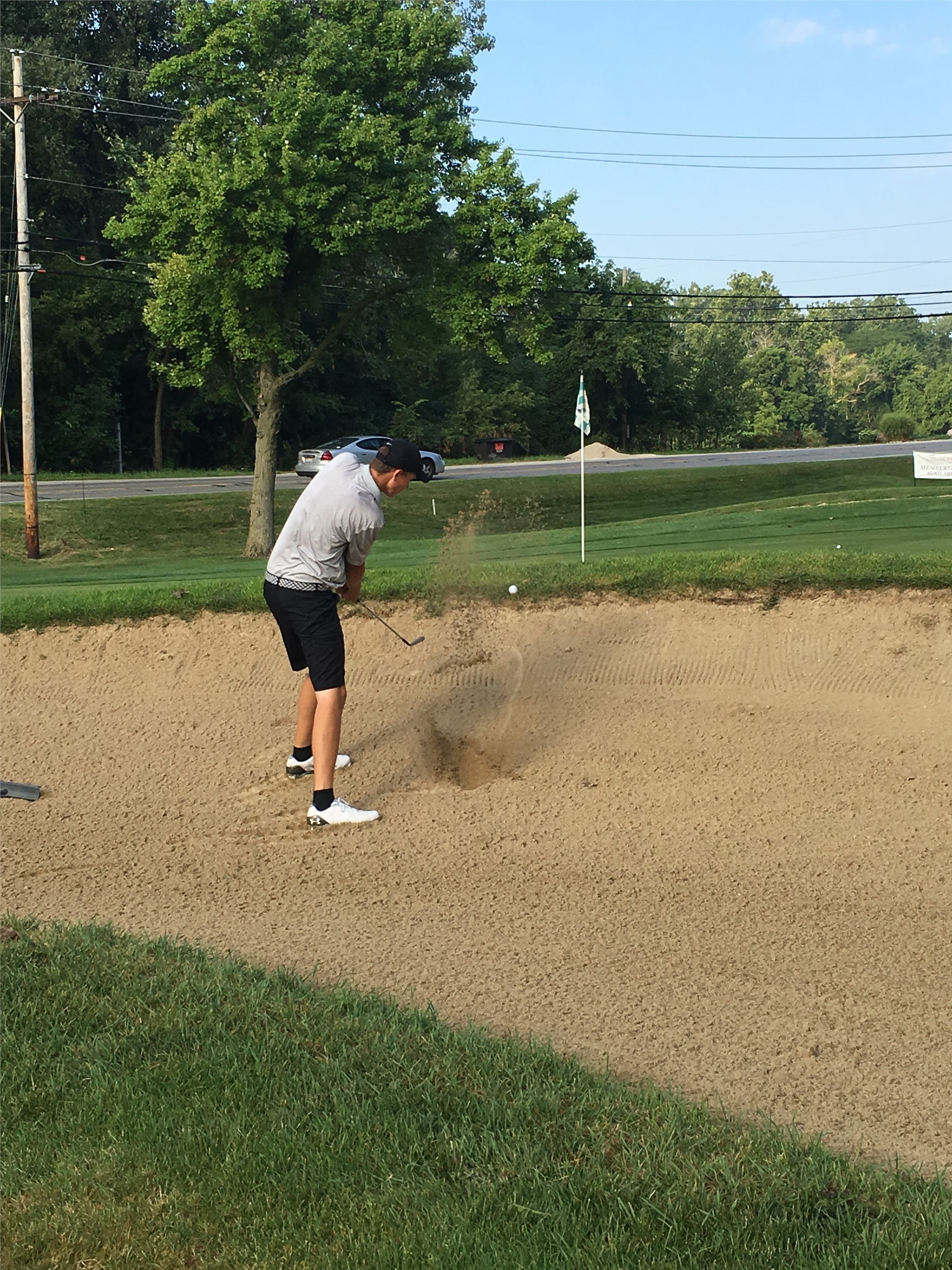 PHS student athlete hitting a golf ball out of the sand
