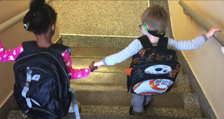 Two preschool students walking down the stairs holding hands