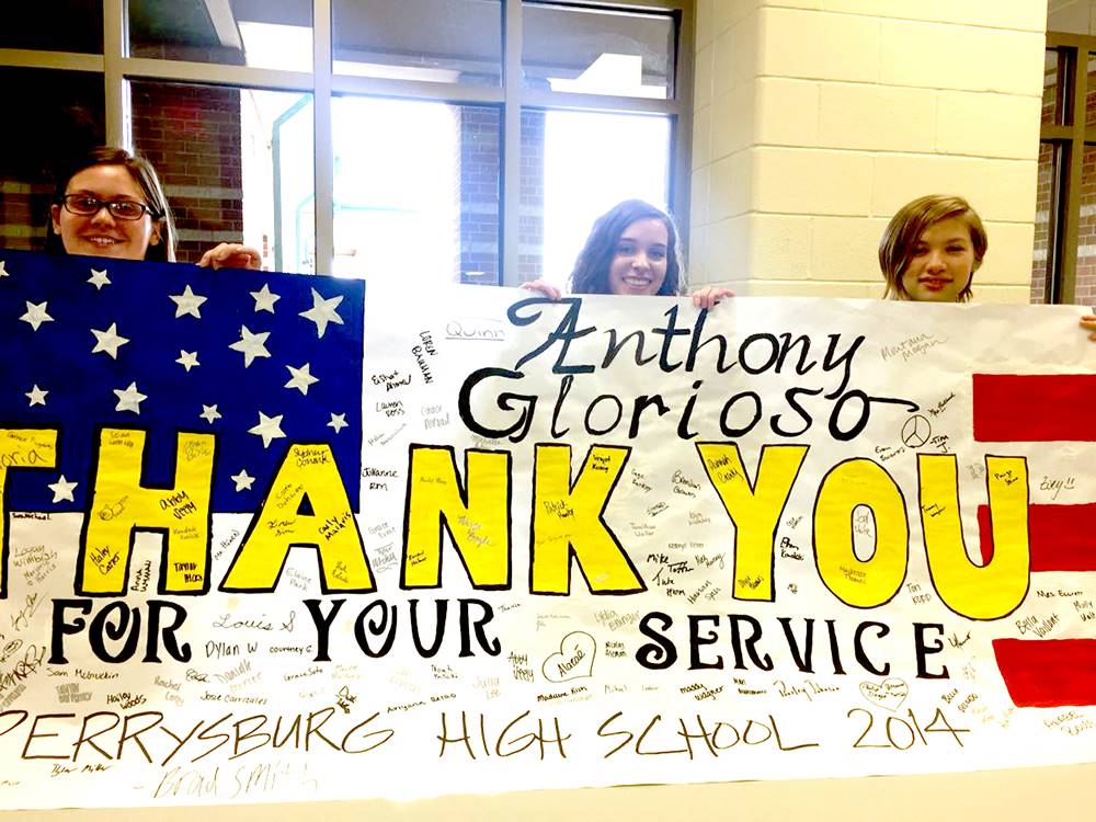 Three students hold banner thanking Anthony Glorioso for his service