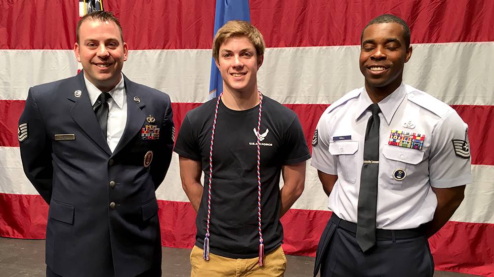 student and two military representatives at signing day