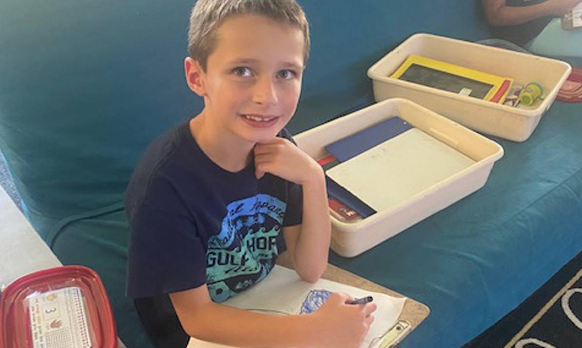 boy writing siting on a couch