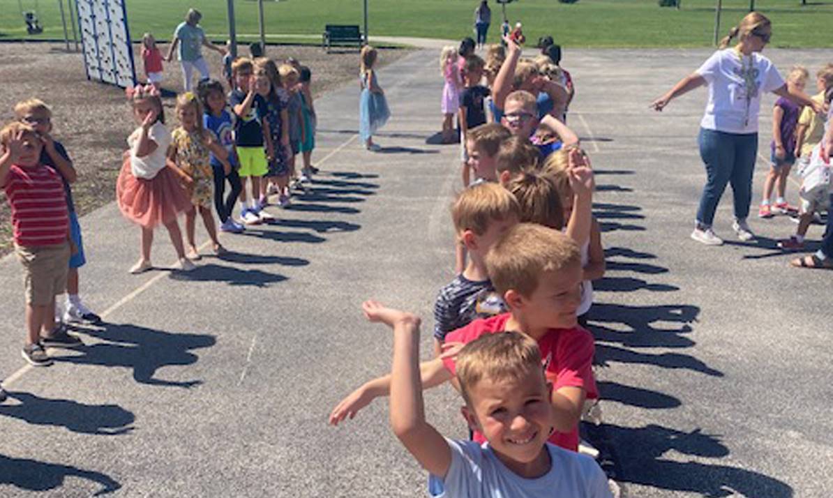 lines of kids waving at the playground