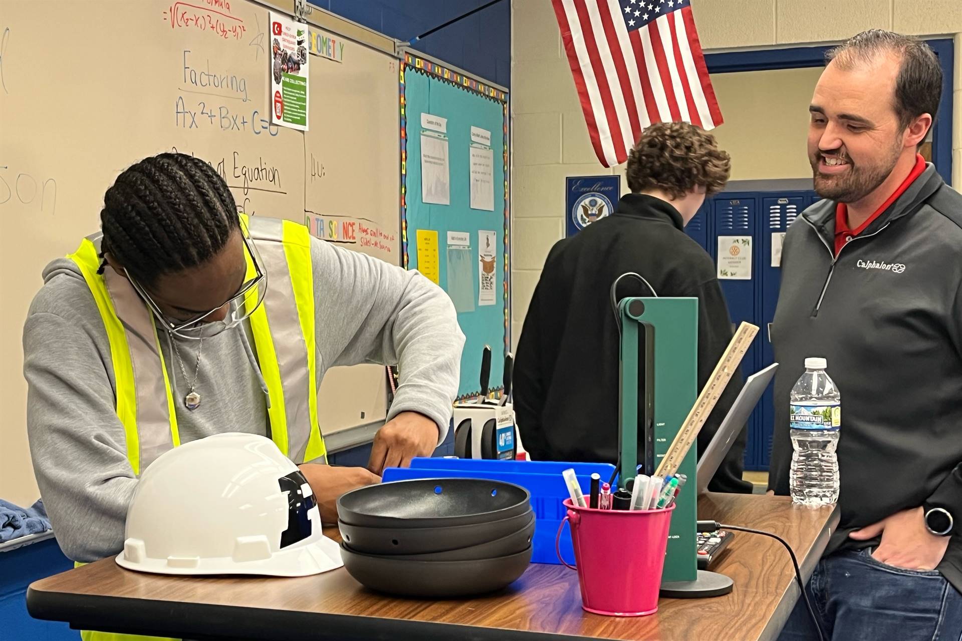 Person working at table while another looks on